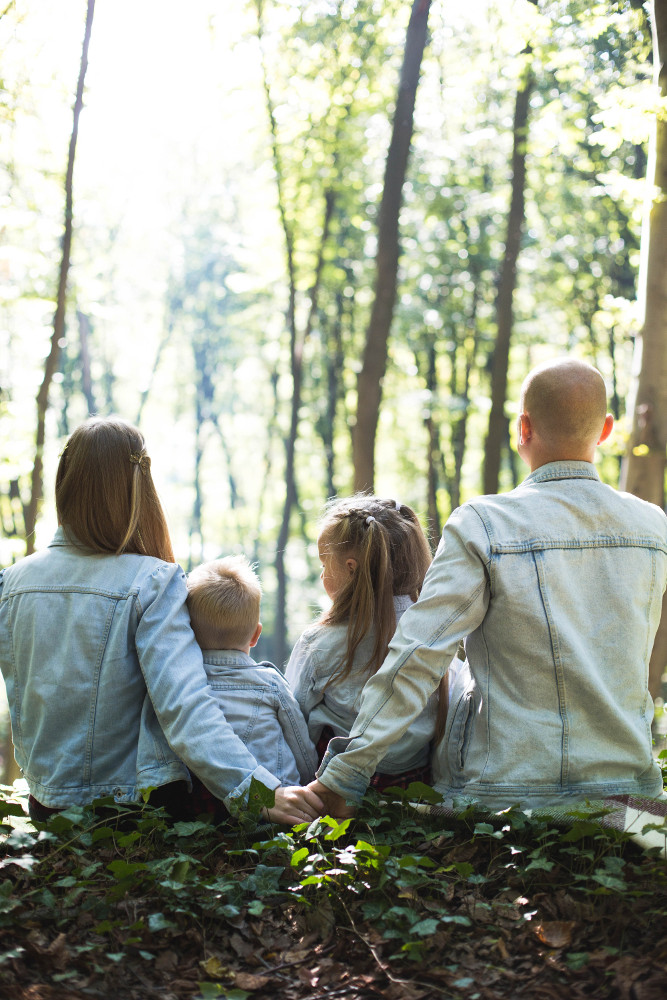 membres d'une famille portant une veste en jean assis dans la forêt