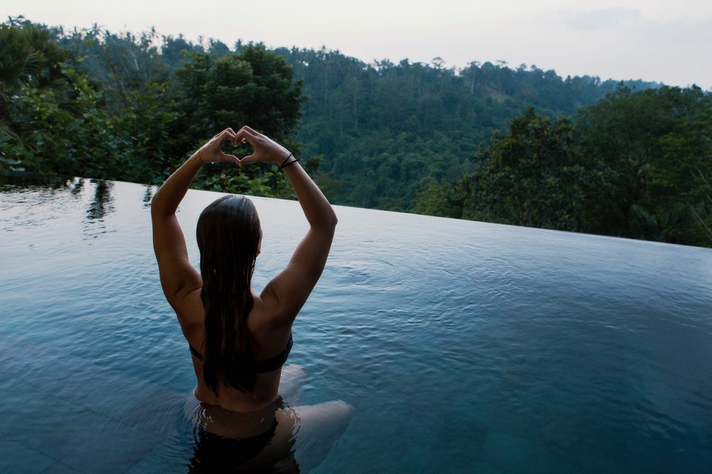 femme assise dans l'eau qui fait un cœur avec ses mains